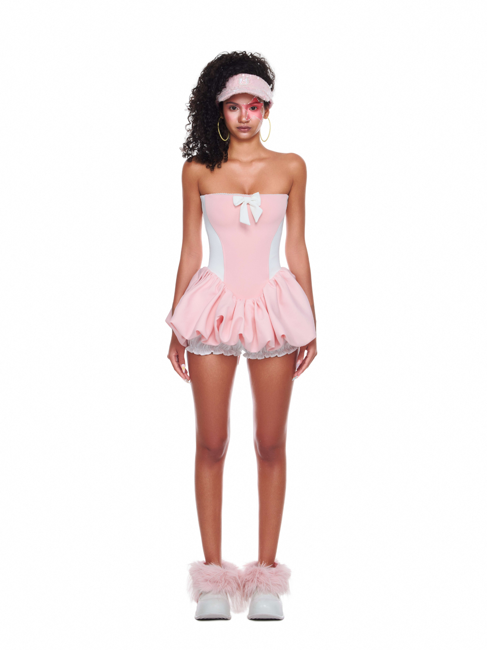 Model wearing strapless blush pink chiffon beach dress with bubble hem and white bow