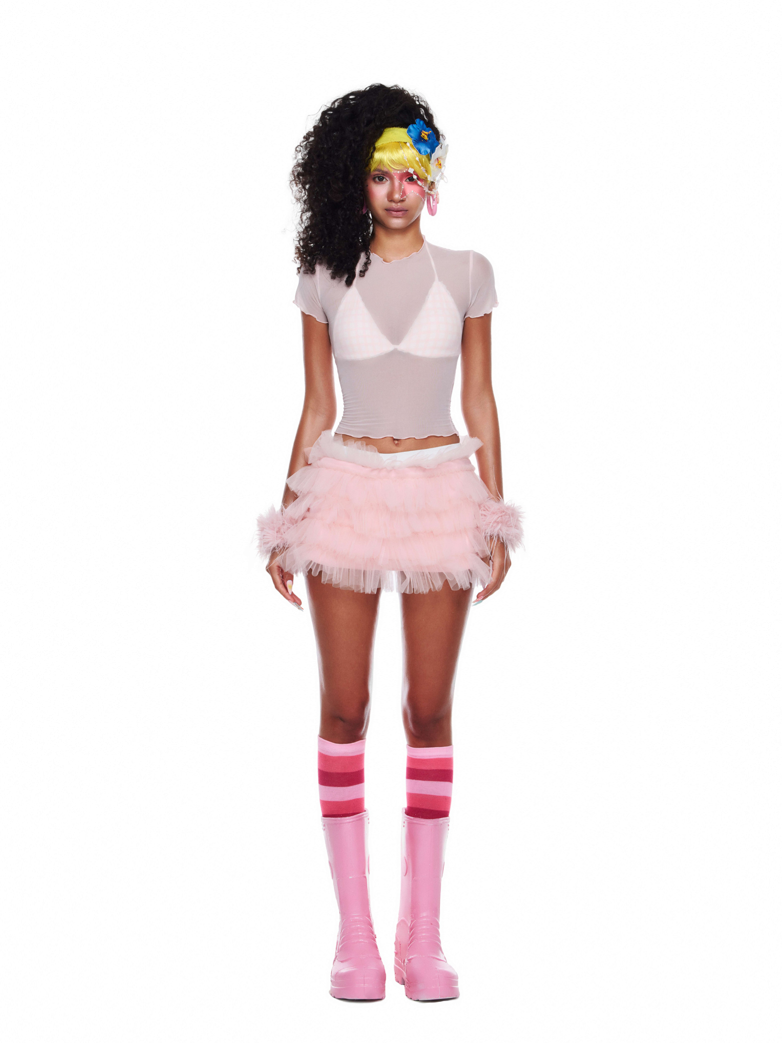 Model in a pastel pink beachwear set with mesh top, gingham bikini, and voluminous tulle skirt, styled with striped socks and boots.