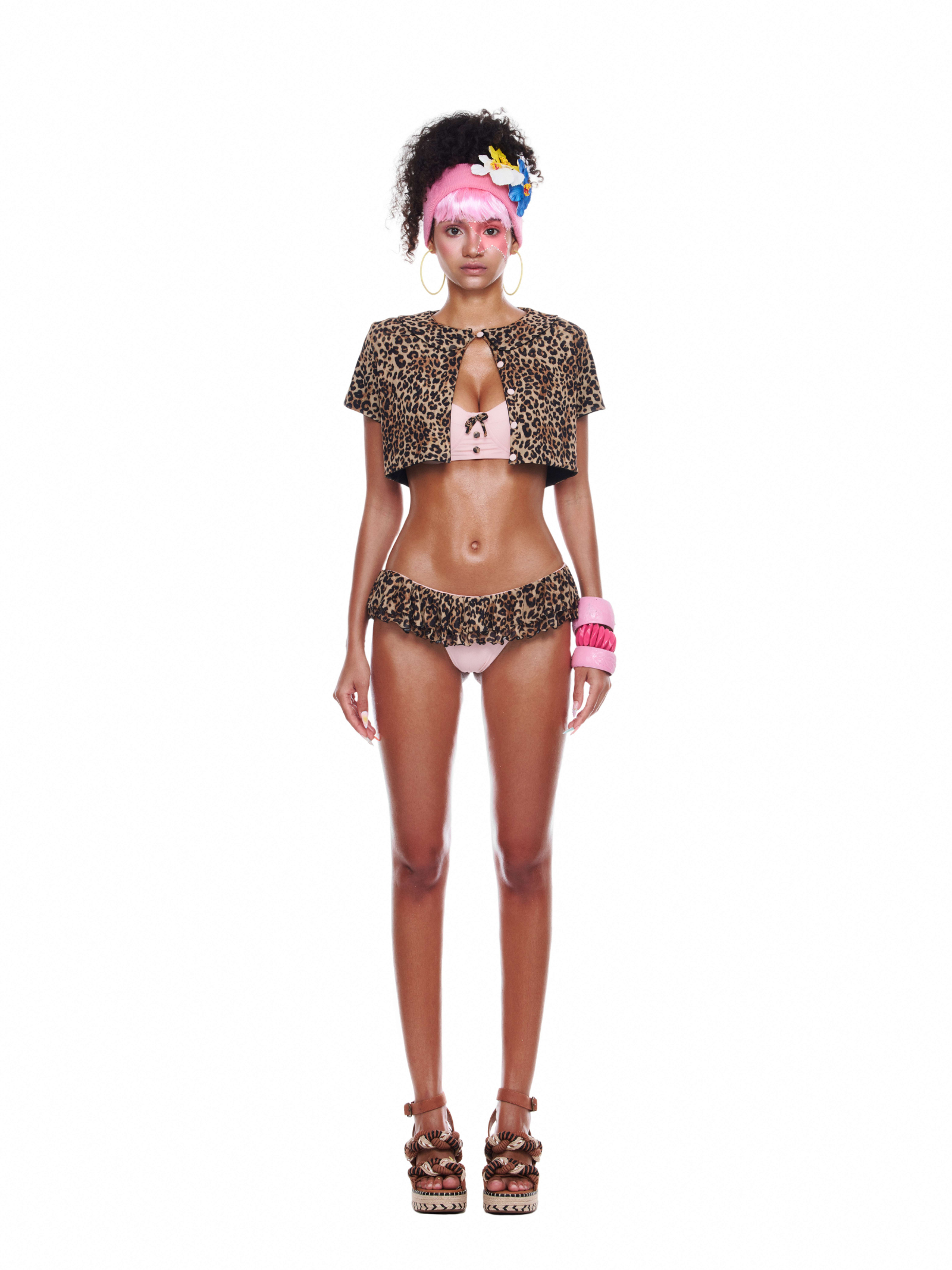 Model wearing the Giselle Set – a leopard bikini set with pink bandeau top, ruffle bottoms, and a short leopard-print cape.