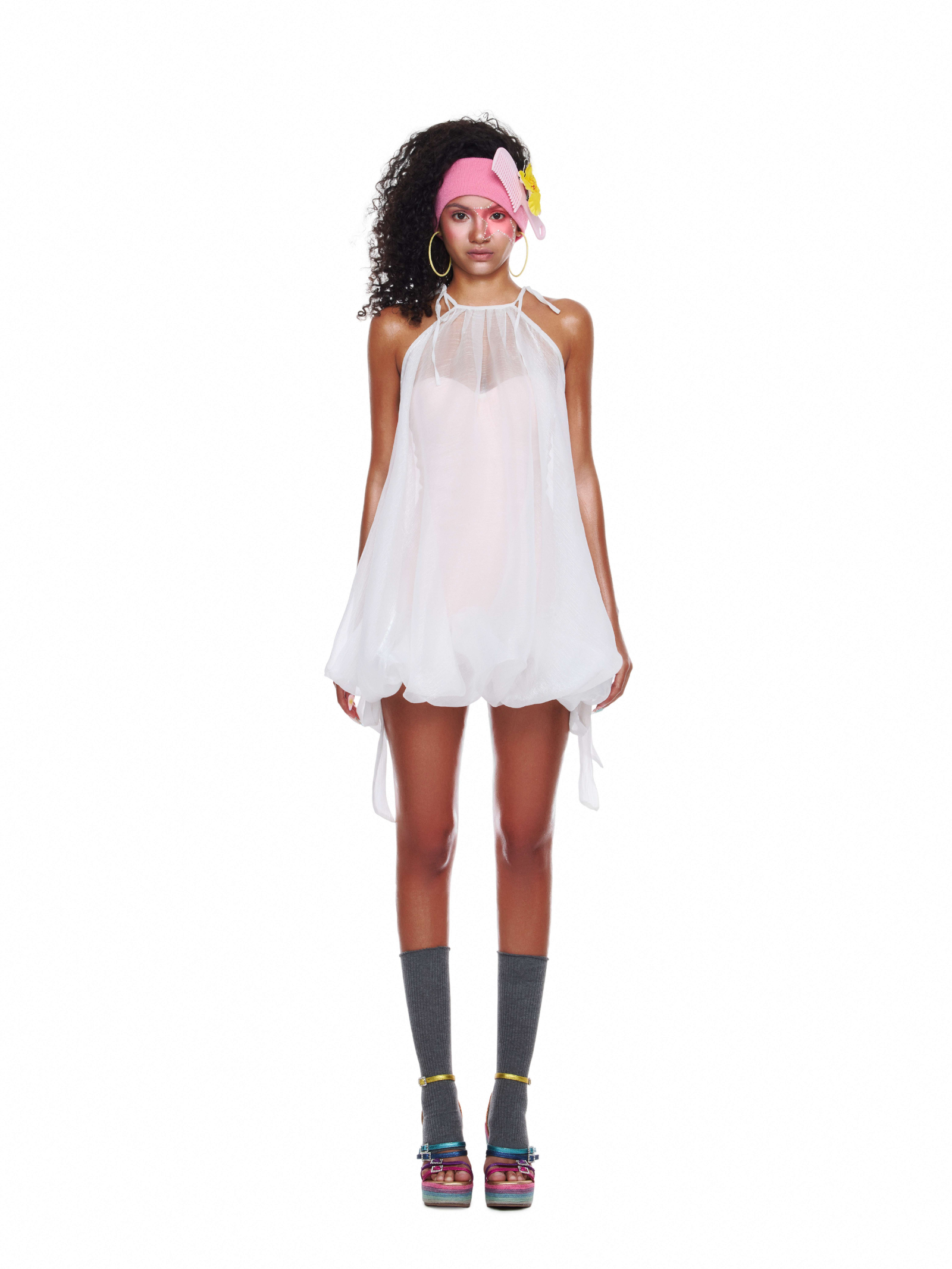 Model wearing a sheer chiffon beachwear dress layered over a fitted bodysuit, styled with socks and platform heels for a dreamy summer look.