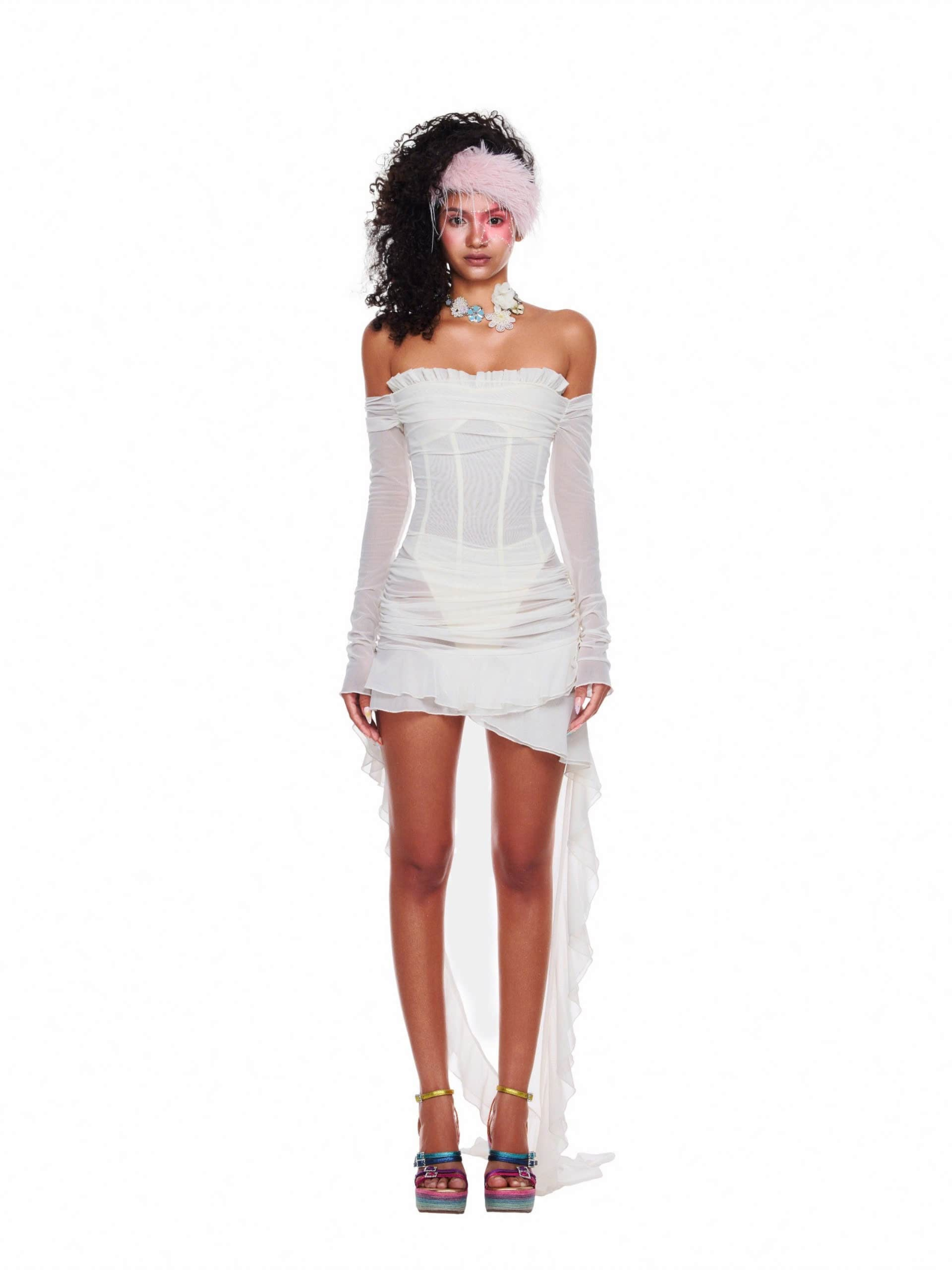 Model wearing a white mesh beach party outfit with off-shoulder corset top and asymmetrical sheer skirt, styled with statement heels and accessories.